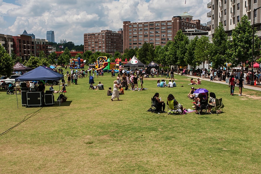 People sit on the grass surrounded by the city during a festival in Old Fourth Ward, Atlanta.